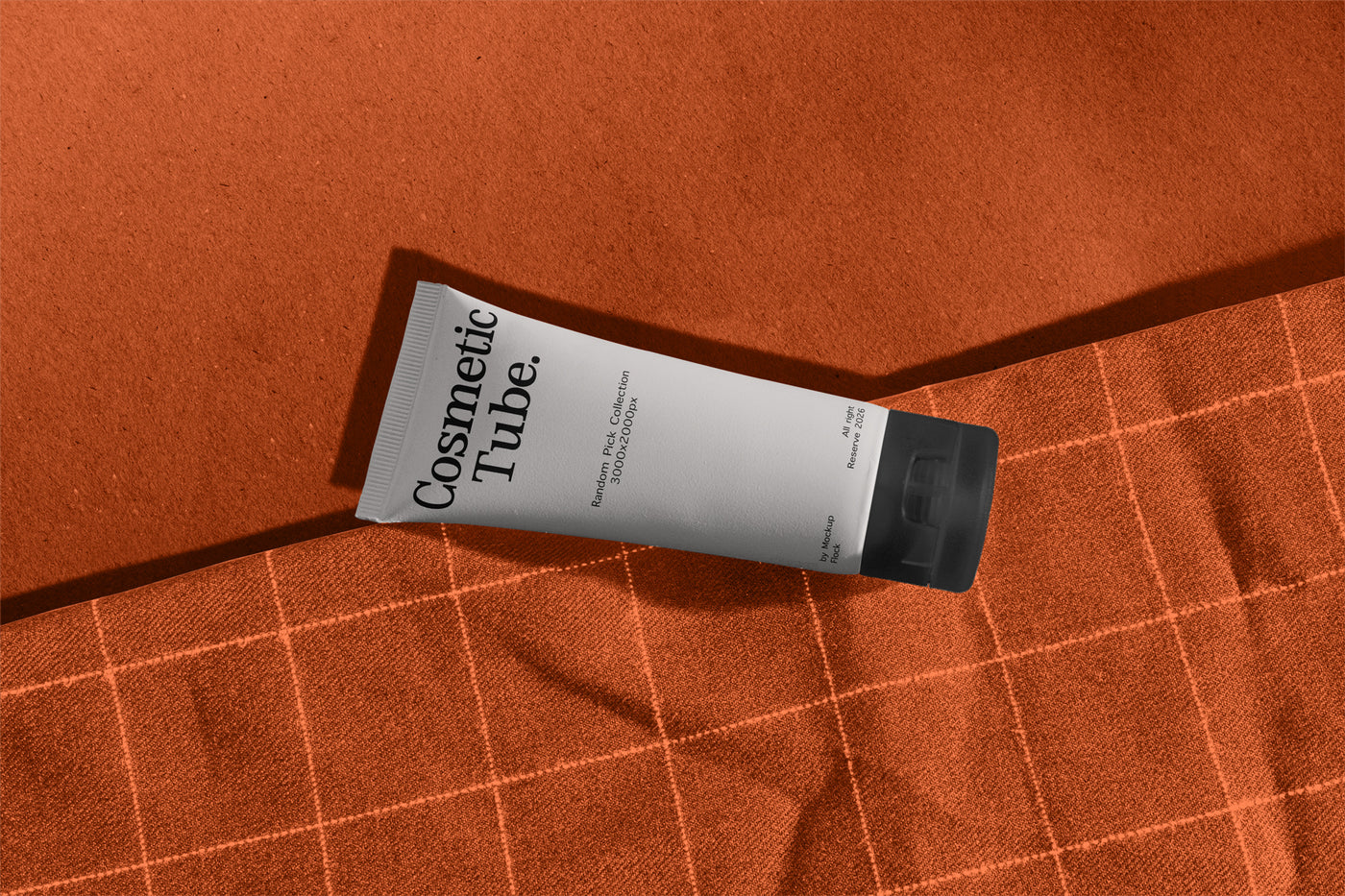 Cosmetic white tube mockup lying diagonally on orange fabric with checkered stitch pattern
