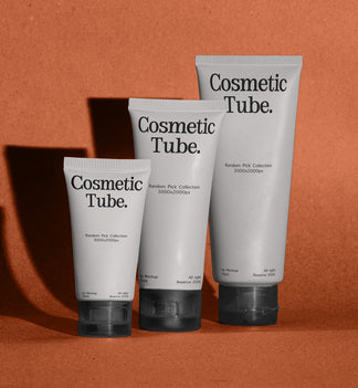 Three white cosmetic squeeze tubes with black caps and black text reading 'Cosmetic Tube.' arranged in a row against a warm terracotta background with cast shadows.