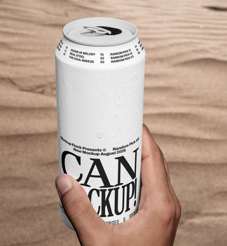 Hand holding a white beverage can mockup upright against a sand dune background, lifestyle mockup