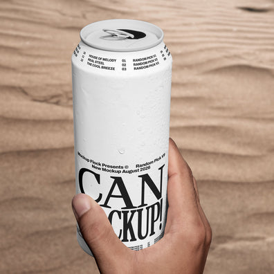 Hand holding a white beverage can mockup upright against a sand dune background, lifestyle mockup