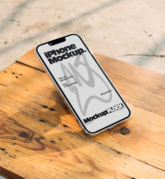 Flat lay view of a white iPhone mockup placed on a rustic wooden table under natural sunlight
