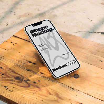 Flat lay view of a white iPhone mockup placed on a rustic wooden table under natural sunlight