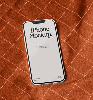 A smartphone mockup with a blank screen reading 'iPhone Mockup.' lies on a rust-orange textured fabric background with a white grid pattern.