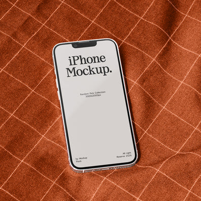 A smartphone mockup with a blank screen reading 'iPhone Mockup.' lies on a rust-orange textured fabric background with a white grid pattern.