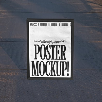Black framed poster mockup standing upright on a dark textured metal floor with soft shadow overlay