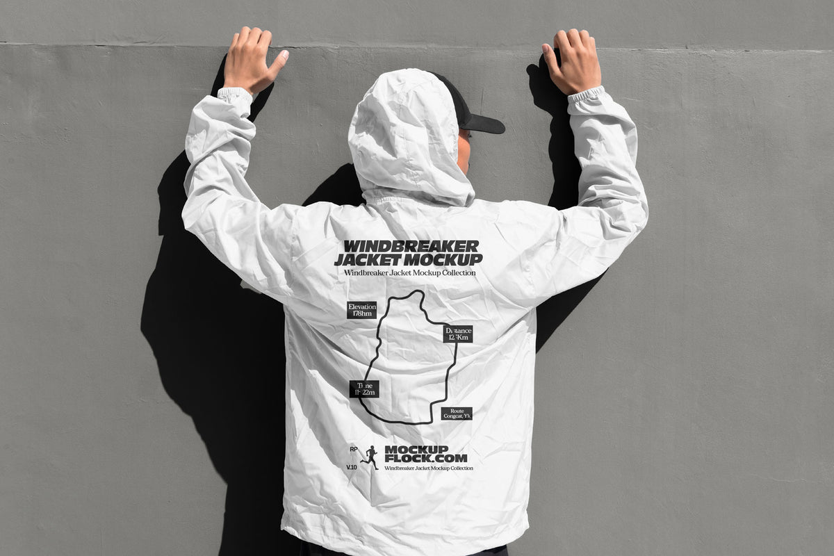 White hooded windbreaker jacket mockup back view with model's hands raised against grey wall